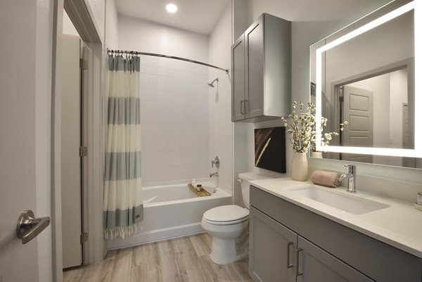 Bathroom with sleek fixtures and marble countertops at The Flats at West Alabama Apartments