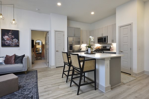 Living room with sleek furniture and natural lighting at The Flats at West Alabama Apartments