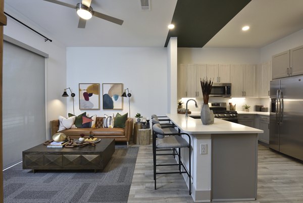 Open-concept kitchen with stainless steel appliances in The Flats at West Alabama Apartments