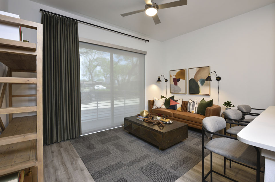 Spacious living room with modern furnishings and natural light at The Flats at West Alabama Apartments
