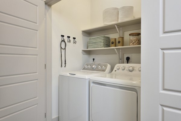 Laundry room featuring modern appliances at The Flats at West Alabama Apartments