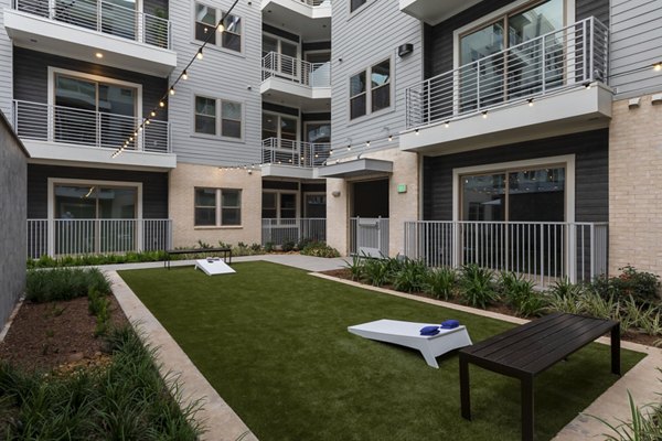 Outdoor recreation area at The Flats at West Alabama Apartments featuring tennis courts and green spaces for an active lifestyle