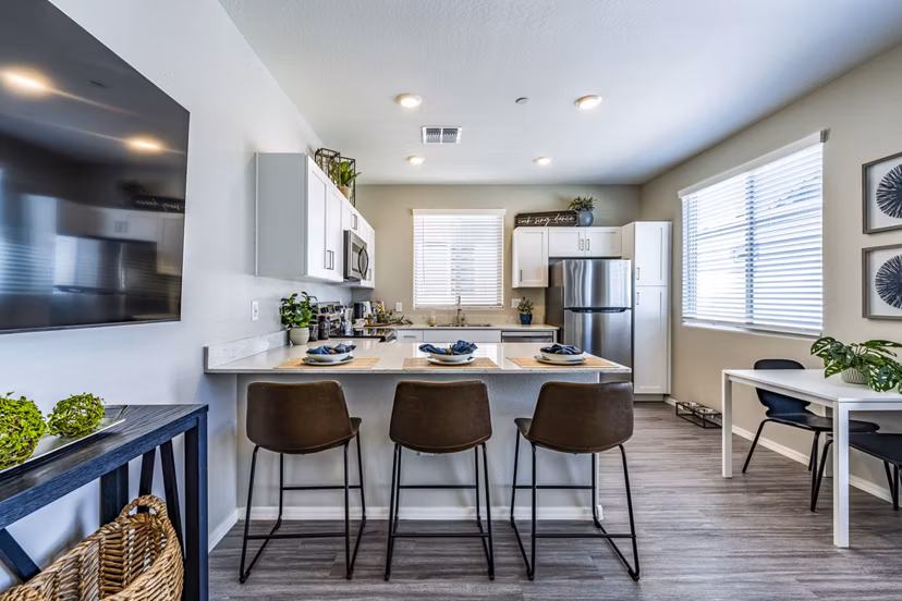 Modern kitchen and dining room with sleek appliances at Vlux at Queen Creek Apartments