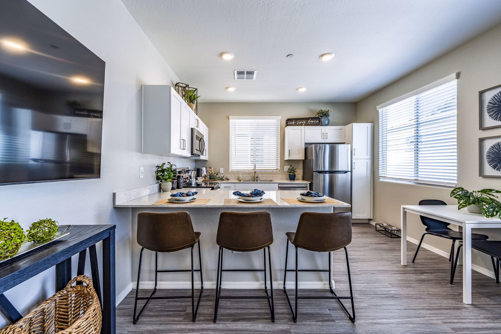 Modern kitchen and dining room with sleek appliances at Vlux at Queen Creek Apartments