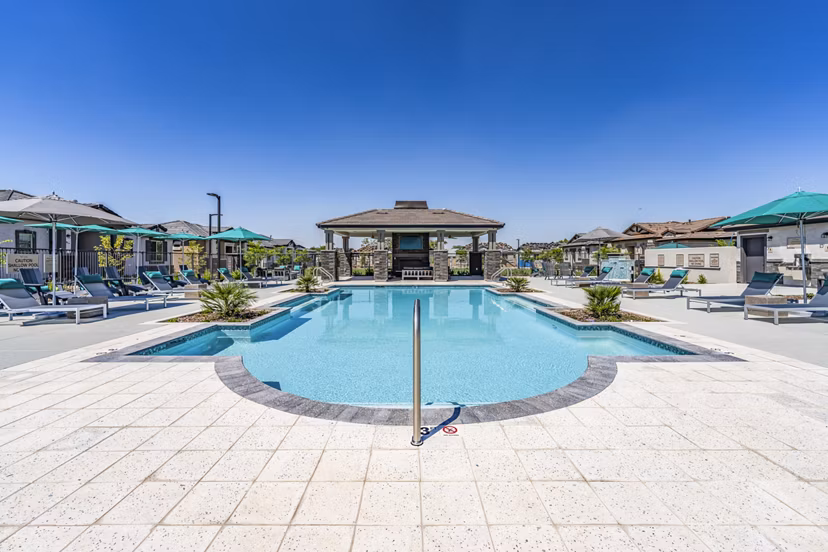 Luxury poolside experience at Vlux at Queen Creek Apartments, featuring lounge chairs and palm trees