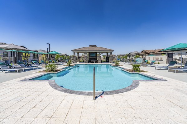 Luxury poolside experience at Vlux at Queen Creek Apartments, featuring lounge chairs and palm trees