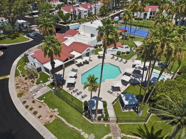 Sun-drenched outdoor pool with lush greenery at La Privada apartments, offering a relaxing setting for residents to unwind and enjoy leisure activities