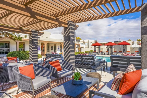 The Aubry Apartments: Relaxing pool patio with modern lounge chairs and surrounded by lush greenery, offering luxury outdoor space