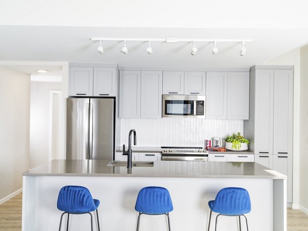 Modern kitchen with stainless steel appliances and quartz countertops in Rigby Apartments
