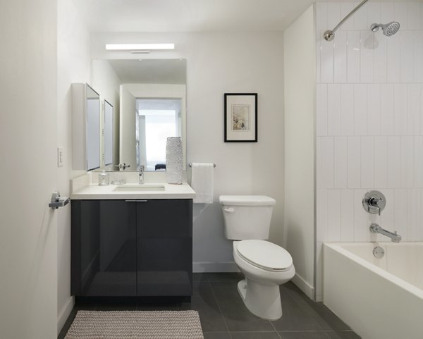 Modern bathroom with sleek fixtures at Eastway Apartments, featuring a large mirror, white vanity, and elegant lighting