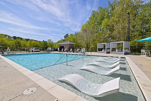 Sparkling pool at Encore at Heritage Apartments with modern lounge chairs, perfect for leisure and relaxation in a luxury setting