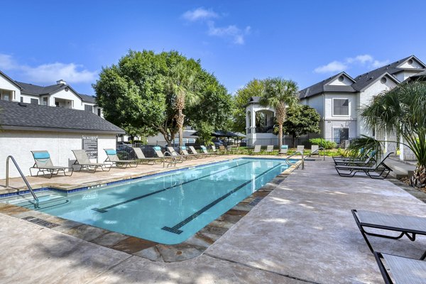 Outdoor pool with lounge chairs at Sendero Ridge Apartments offering luxury amenities