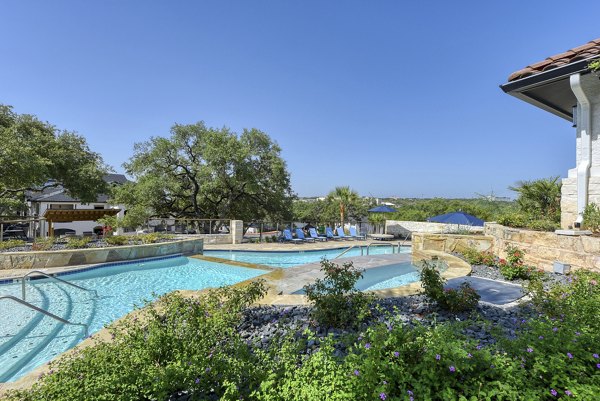 Outdoor pool area with shaded lounge chairs at Sendero Ridge Apartments