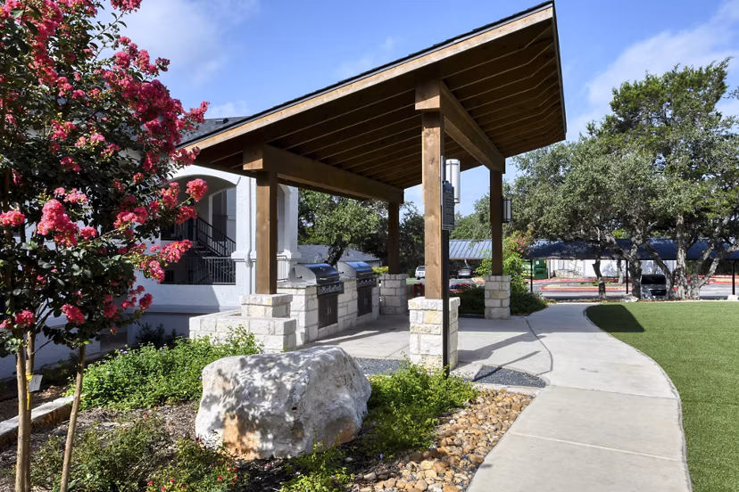 Recreational area featuring landscaped gardens and picnic tables at Sendero Ridge Apartments