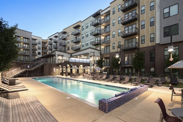 Riverside pool with modern lounge chairs at River House Apartments, offering luxury outdoor leisure in a tranquil setting