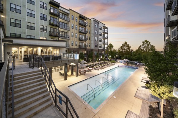 Modern outdoor pool at River House Apartments with poolside lounge chairs and landscaped gardens, offering luxury living in a serene setting