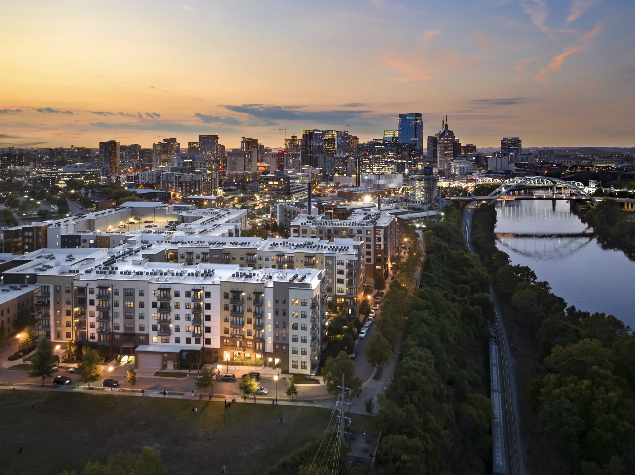 Cityscape at sunset with buildings and a bridge over the river near luxury apartments