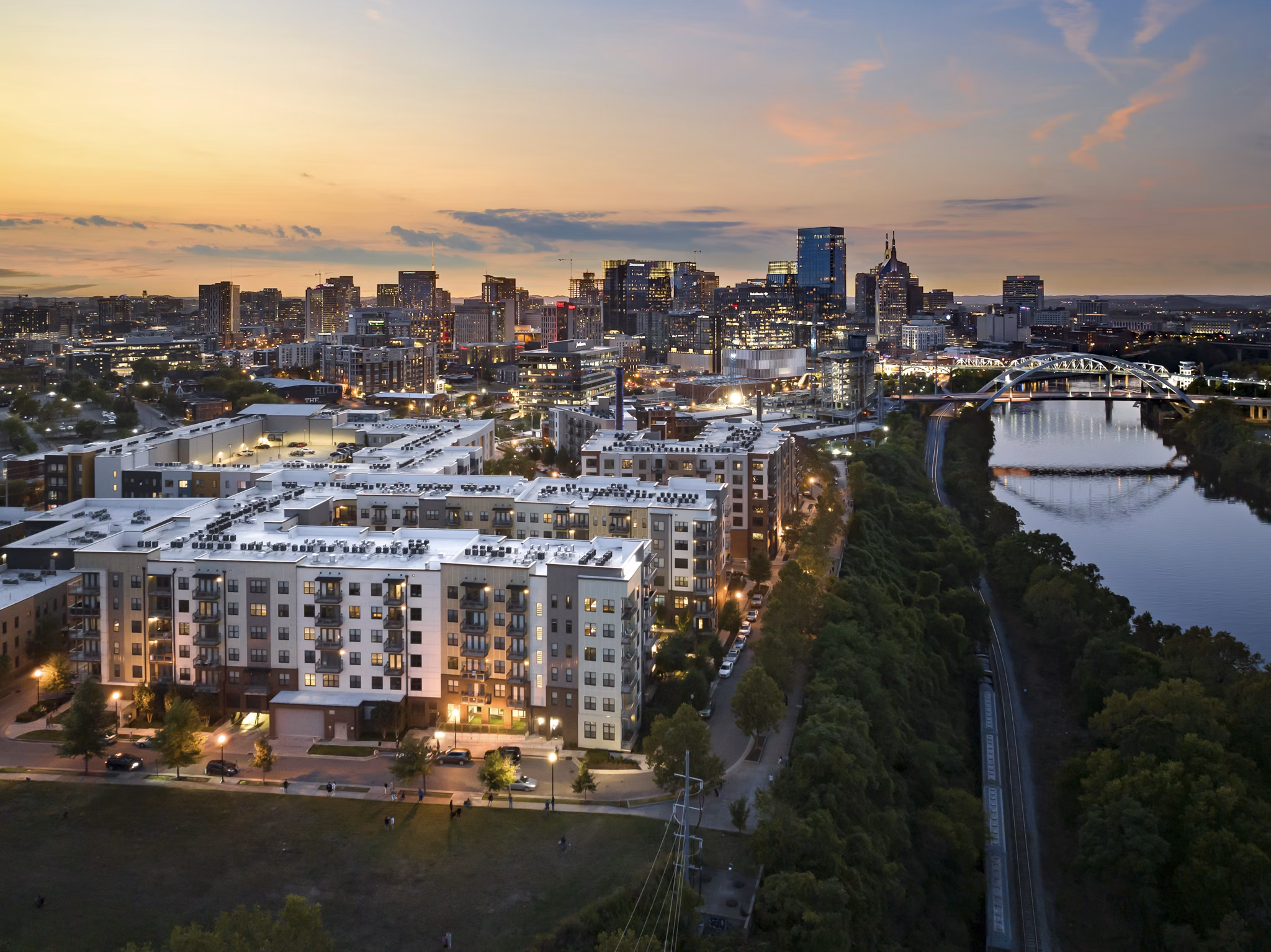 Cityscape at sunset with buildings and a bridge over the river near luxury apartments
