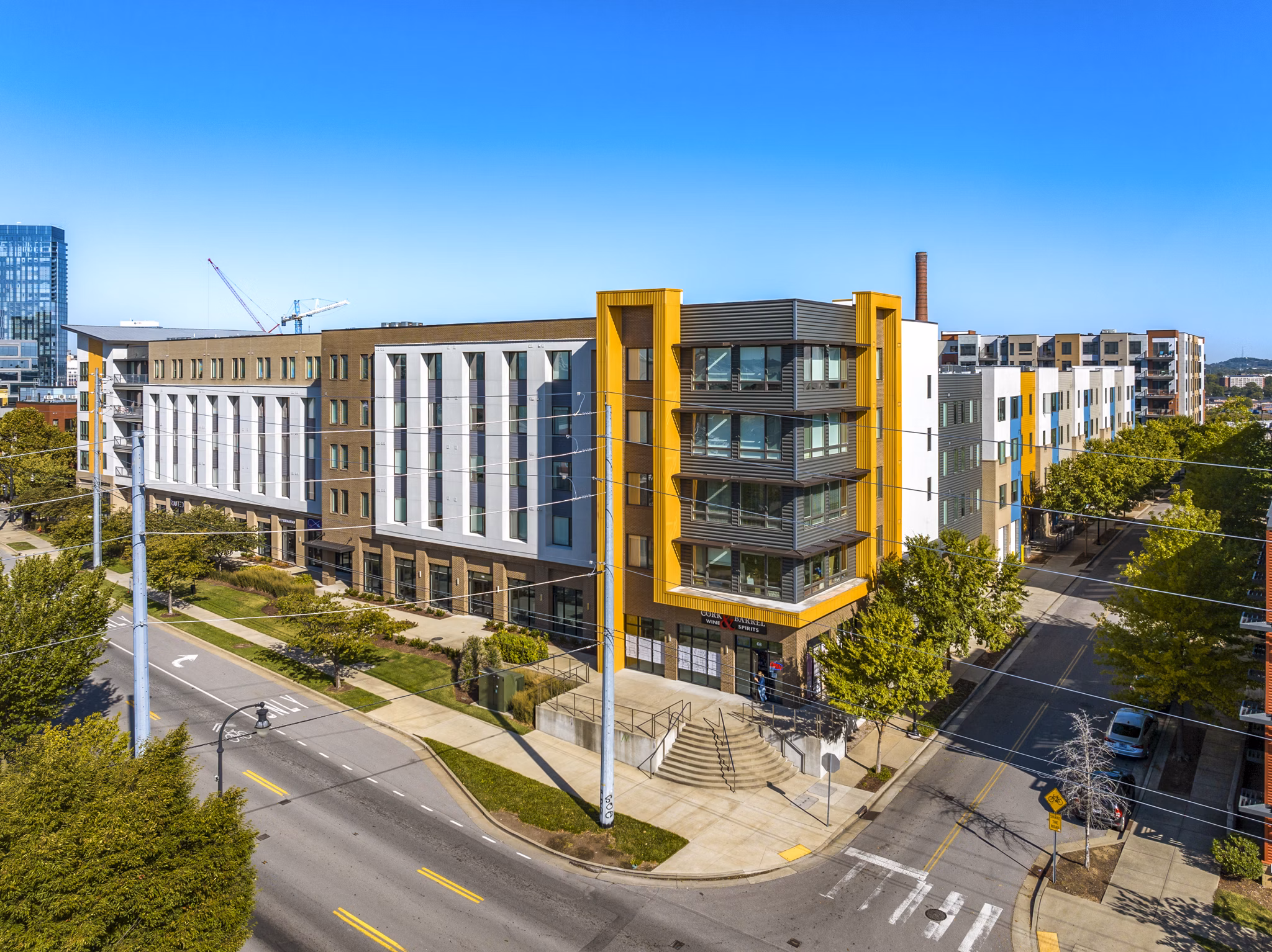Modern luxury apartments on a sunny street corner with trees and blue sky