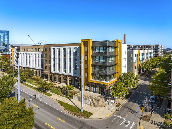 Modern luxury apartments on a sunny street corner with trees and blue sky