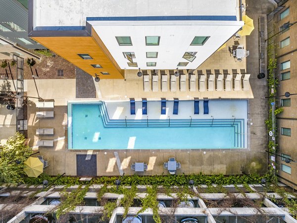 Aerial view of a vibrant swimming pool area with lounge chairs at luxury apartments