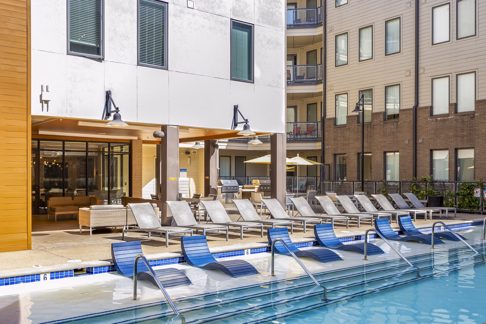 Luxurious poolside view at Terra House Apartments, featuring lounge chairs and modern design Enjoy summer relaxation at this premium location