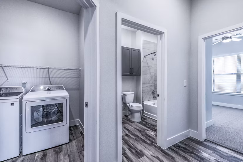 Laundry area and modern bathroom with sleek design at Larkspur at Creekside Apartments, featuring spacious countertops and in-unit washer and dryer
