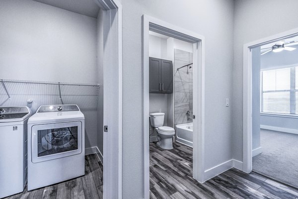 Laundry area and modern bathroom with sleek design at Larkspur at Creekside Apartments, featuring spacious countertops and in-unit washer and dryer