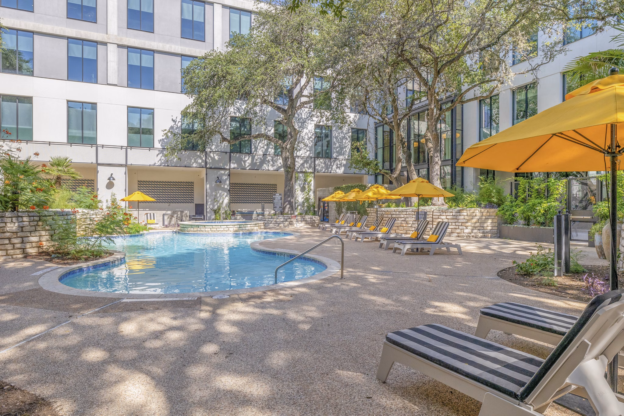 The Lola Apartments: Relaxing pool area with modern loungers and greenery