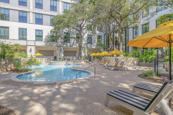 The Lola Apartments: Relaxing pool area with modern loungers and greenery