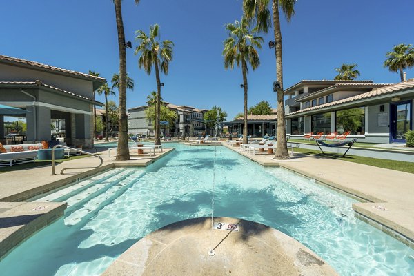 Resort-style pool area at Gateway at Tempe Apartments with lounge chairs and palm trees