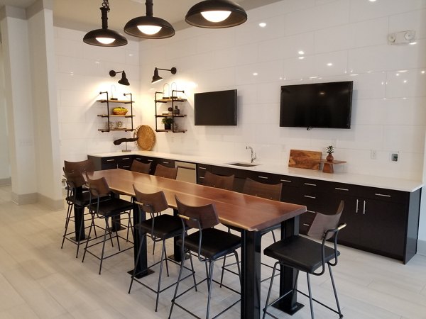 Modern clubhouse with elegant seating and large TV at The Peak at Nichols Plaza Apartments