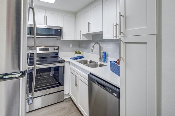 Modern kitchen with sleek appliances and granite countertops in 7 West Apartments