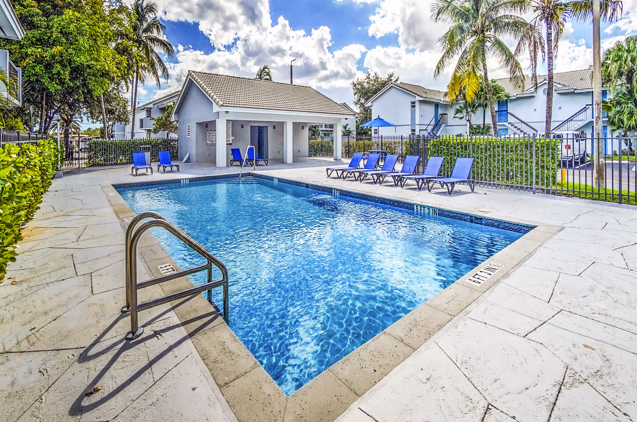 Sunny outdoor pool area with comfy loungers at 7 West Apartments
