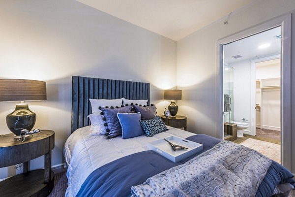 Modern bedroom featuring sleek decor and large windows at The Travis Apartments
