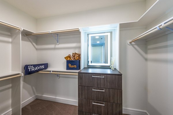 Walk-in bedroom closet with custom shelving in The Travis Apartments, offering luxury storage solutions in a sophisticated setting