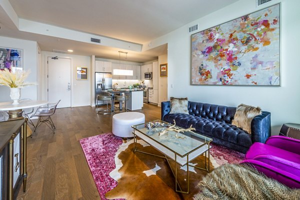 Spacious living room with modern decor and large windows at The Travis Apartments