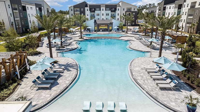 Resort-style pool at Grand Cypress Apartments, offering luxury living with ample poolside seating and lush landscaping