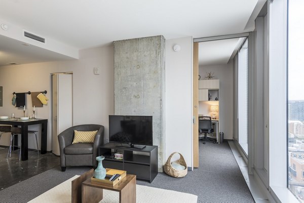 Living room with modern decor and large windows at Evo at Cira Centre South Apartments, offering luxury living in a Greystar community