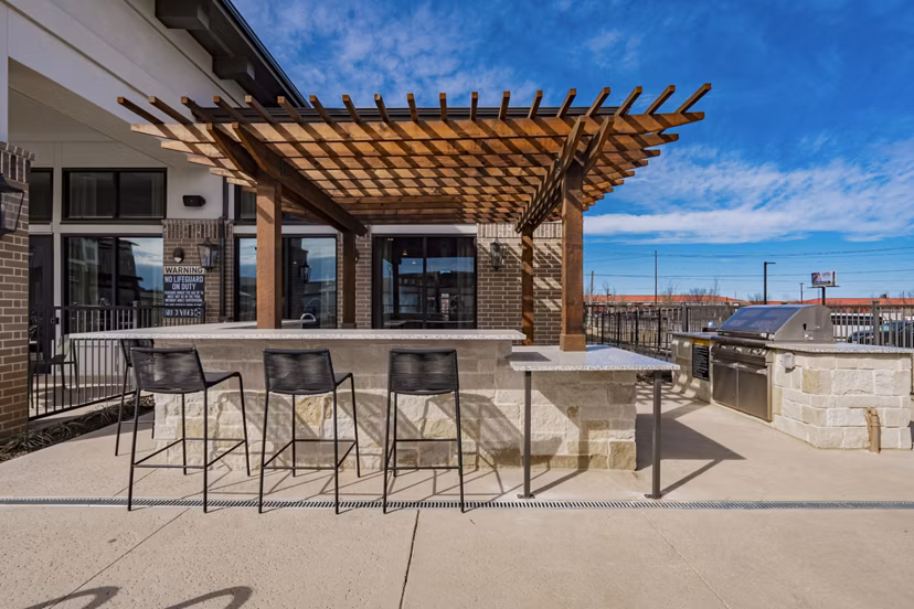 Outdoor communal grill area at The Lyric at Keller Center apartments featuring modern BBQ facilities in vibrant community setting