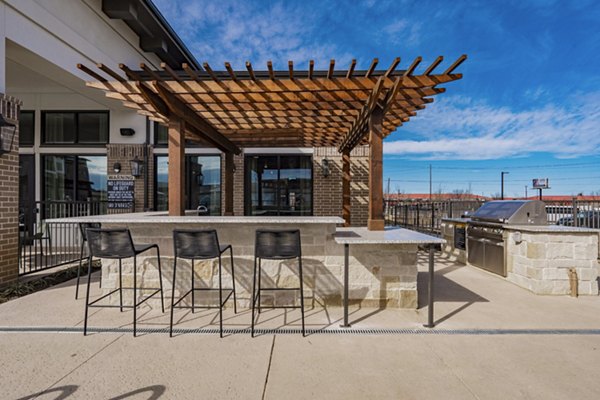 Outdoor communal grill area at The Lyric at Keller Center apartments featuring modern BBQ facilities in vibrant community setting