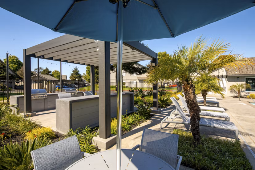 Grill area with seating and shade at Windscape Village Apartments