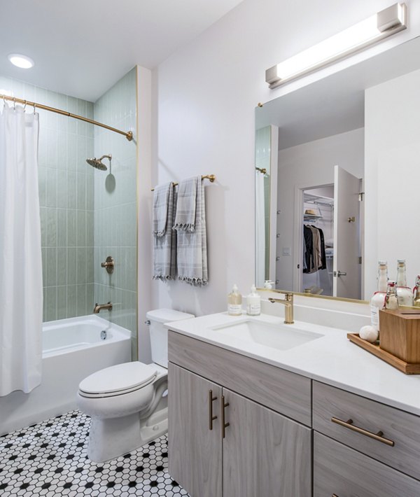 Bright bathroom with white tiles, bathtub, and wooden vanity at The Lucie Apartments