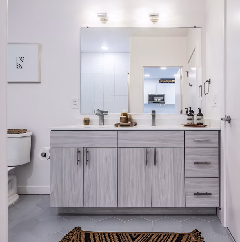 Bathroom featuring double sink vanity, large mirror, and wall art at The Lucie Apartments luxury property