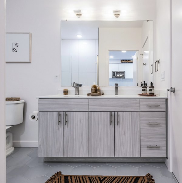 Bathroom featuring double sink vanity, large mirror, and wall art at The Lucie Apartments luxury property
