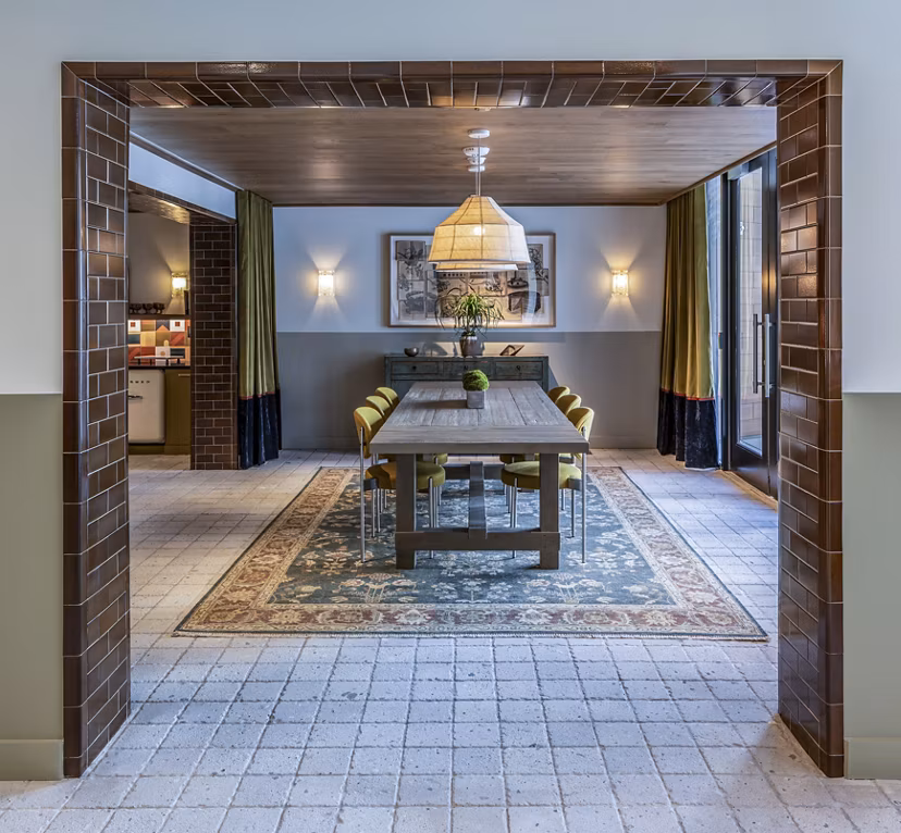 Dining room with long table, pendant light, and wall sconces at The Lucie Apartments: elegant dining area in Greystar luxury community