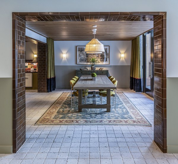 Dining room with long table, pendant light, and wall sconces at The Lucie Apartments: elegant dining area in Greystar luxury community