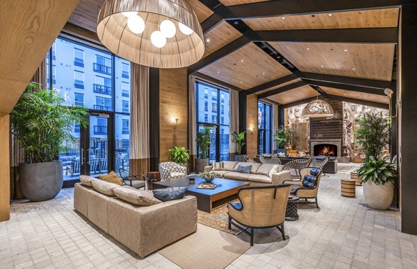 Modern lounge area with sofas, plants, and large windows at The Lucie Apartments.