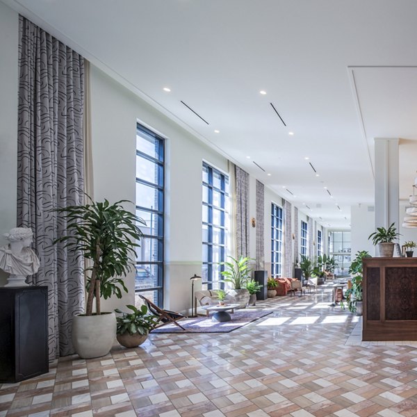 Modern lounge with sofas, plants, and large windows in The Lucie Apartments