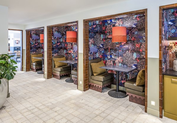 Three cozy dining booths with floral wallpaper and red lamps at The Lucie Apartments, offering a stylish dining experience in luxury living